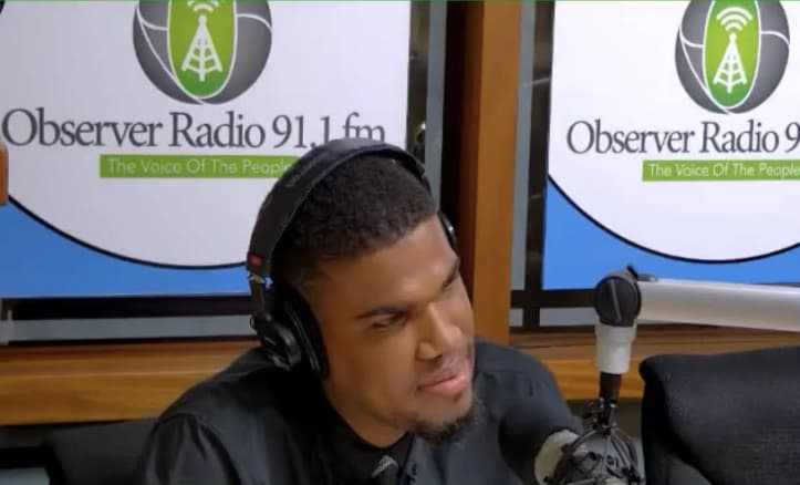 JW on radio in black shirt and black and grey tie